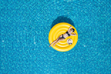 Beautiful young asian woman with yellow inflatable ring relaxing in swimming pool. top view
