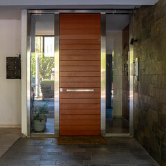 Modern residential building entrance stainless steel and wood door, Athens, Greece.
