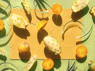 Exotic fruits, yellow and orange prickly pears. Healthy cactus fruits on lime green, orange background. Direct sunlight with shadows. Wet background with traces of water, flat lay from above.