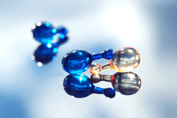 Serum capsules for healthy skin. Anti-wrinkle rejuvenation skin treatment. Beauty product presentation, close-up in blue and orange colors.