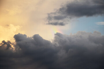 Fototapeta na wymiar Rainy sky with rainbow on sunset background