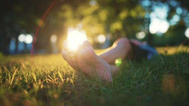 Bare feet of a child in the green grass of a sunny park in summer. The concept of the first steps, happy childhood. Summer vacation.