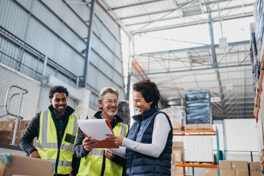 Happy warehouse workers looking at a report during a meeting