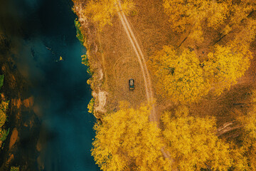 Car Renault Duster SUV parked near river landscape. Aerial view of yellow forest woods and river in autumn landscape. Top view of beautiful european nature from high attitude in autumn season. Bird's - obrazy, fototapety, plakaty