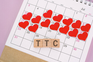 TTC word on wooden block with red heart shape on calendar. Trying To Conceive.