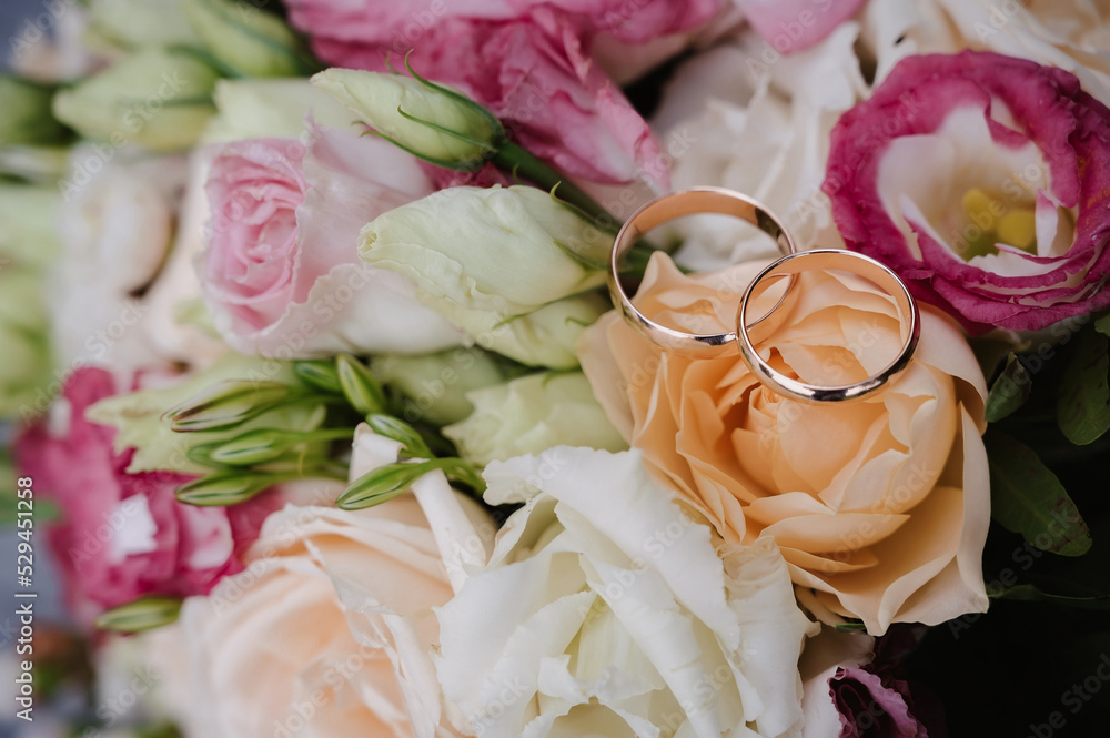 Wall mural pair of gold wedding rings on the bride's bouquet on the day of the ceremony