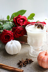 original candle made of natural soy wax in a glass goblet. Autumn composition with pumpkins and leaves. Halloween and thanksgiving concept.
