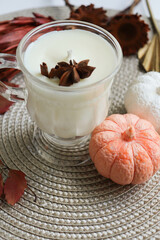 original candle made of natural soy wax in a glass goblet. Autumn composition with pumpkins and leaves. Halloween and thanksgiving concept.