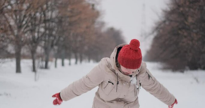 Young woman in red knitted hat rejoices in winter and tosses up snow and . Photo shoot in the winter park backstage