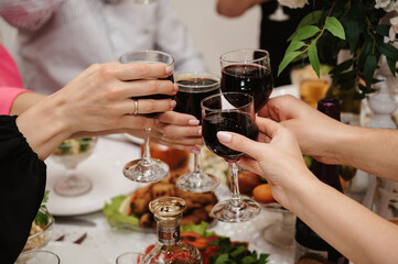 group of friends clink glasses with wine and celebrate the holiday at a festive table