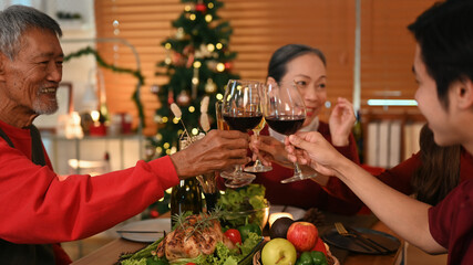 Young coupler celebrating Christmas or New Year with grandparents and clinking glass of wine. Christmas and thanksgiving concept