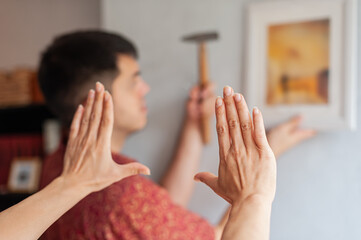 Young couple decorates their new apartment with painting on the wall