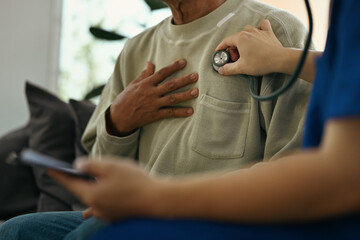 Cropped shot of doctor holding stethoscope checking heart and lungs of elderly male patient