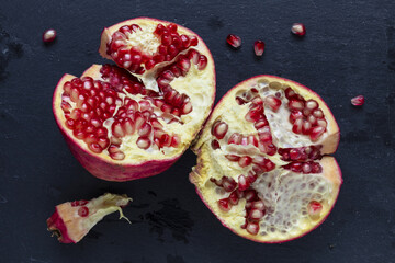 Open pomegranate on a dark black background, low key food still life photography
