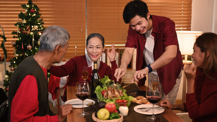 Grandparents celebrating Christmas or New Year with young coupler at cozy home. Holidays and celebration concept