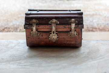 An old rusted treasure chest laid on a cement floor.