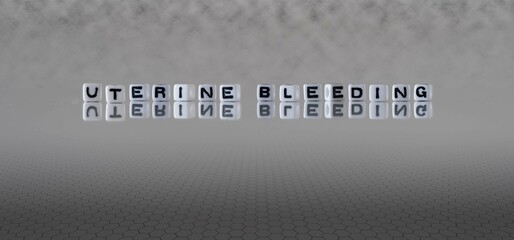 uterine bleeding word or concept represented by black and white letter cubes on a grey horizon background stretching to infinity