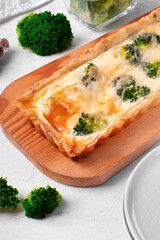 Broccoli tart on shortbread dough of rectangular shape on wooden board. Savory pie with vegetable