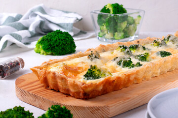 Broccoli tart on shortbread dough of rectangular shape on wooden board. Savory pie with vegetable