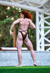 girl weightlifter performs on stage shows tense muscles in various poses, demonstrating the beauty...