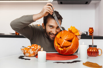 An expressive man preparing a pumpkin for Halloween