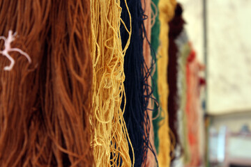selective focus photo of bundles of colorful rope hanging side by side, rainbow colored silk thread...