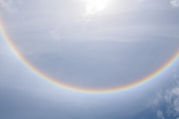 Rainbow colors around the sun among the clouds and sky. fantastic beautiful sun halo phenomenon.