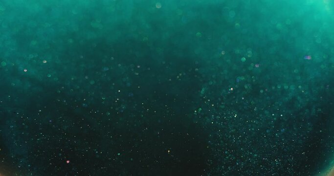 Bokeh light background. Blur glitter. Bubbles floating in water. Defocused verdigris green orange color particles on dark abstract vertical texture. Shot on RED Cinema camera.