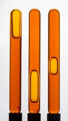 Yellow viscous liquid sunflower lecithin with bubbles in a transparent test tube on a white background