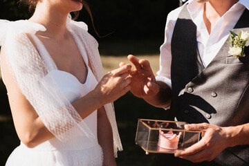bride's hand puts a gold ring on the groom's finger on the wedding day during the ceremony