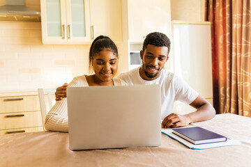 African american couple managing finances bank and using laptop at kitchen