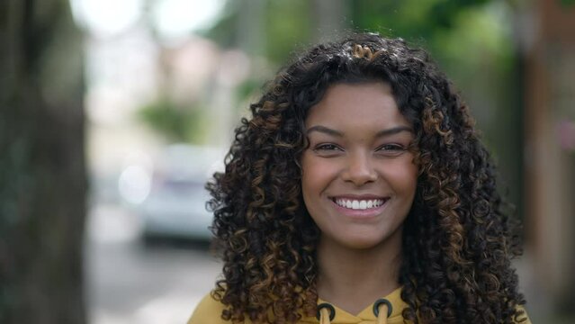 One happy black girl smiling. Portrait of a joyful African American young woman with curly hair. Female person with authentic real life laugh and smile