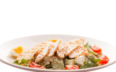 Caesar salad with chicken, white bread croutons, fresh lettuce, tomato and arugula on a white background