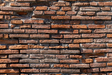 Naklejka premium Red Bricks of a facade wall in Pompeii. Building made by roman masonry craftsmen 2000 years ago. Historic excavations are a major sight and world heritage in Campania near Naples and mount Vesuvius.