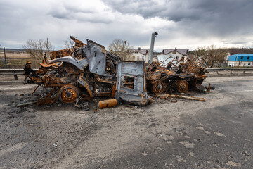 Fototapeta premium Hostomel, Kyev region Ukraine - 09.04.2022: Burnt military vehicles of Russian soldiers on the bridge across the river. Cars after being hit by rockets, mines. Rusty cars. Charred car parts.