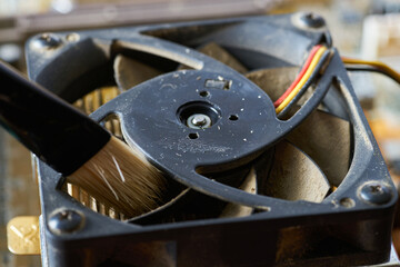 Cleaning dirty desktop computer processor fan from dust by special brush close up.