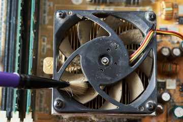 Cleaning dirty desktop computer processor fan from dust by special brush close up.