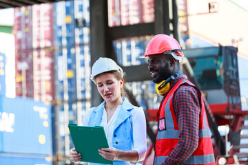 A team of African American men and Caucasian women wear helmets. Work on controlling the loading of containers from cargo ships