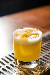 A vertical shot of a whiskey sour cocktail at a bar counter