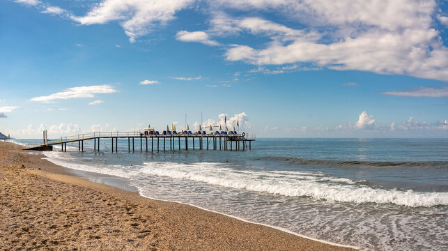 Background image of seascape of mediterranean resort coast with calm sea, sandy beach and pier.