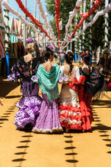 Women in flamenco dresses during fair in city - obrazy, fototapety, plakaty
