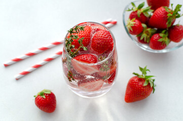 Detox strawberry thyme infused water or mocktail in a glass on white background