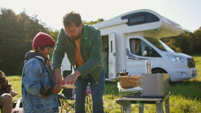 Three generations spending time together during camping with camper van at autumn nature.