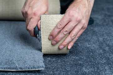 Handyman cutting a new carpet with a carpet cutter.