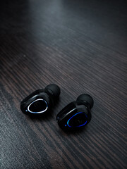 Obraz na płótnie Canvas Black wireless earphone or Airpods wireless headphone and charging case on table for using with smartphone. Technology concept