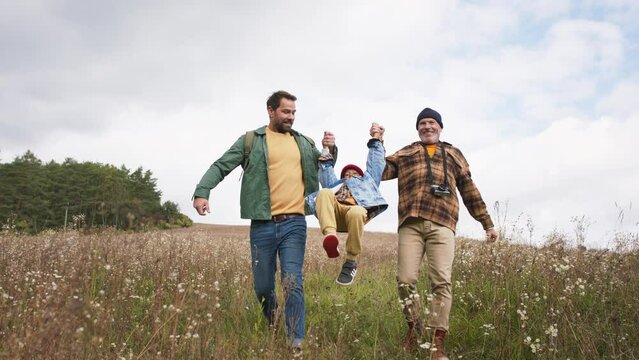 Three generations of men walking together at meadow, discovering nature.