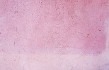 Plastered wall covered with pink paint. The wall of a city house. Pink background.