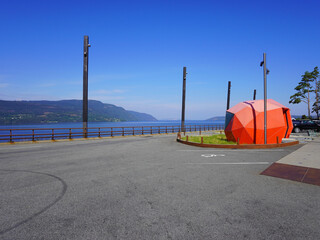 Ein Rastplatz in Norwegen mit Blick auf einen See und einem orangefarbenen Toilettenhäuschen
