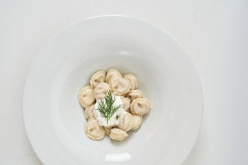 dumplings with sour cream with herbs on a white plate