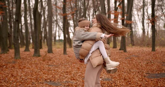 Beatiful mom holding daughter in hands in forest